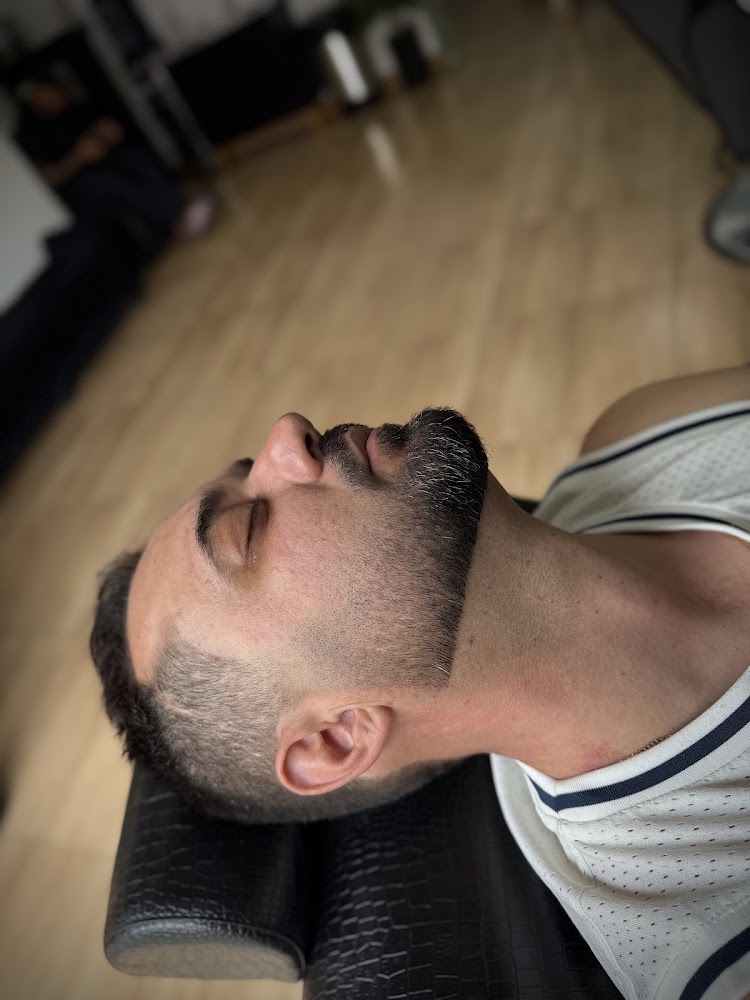 Cliente recostado na cadeira da barbearia após corte com degradê e barba alinhada